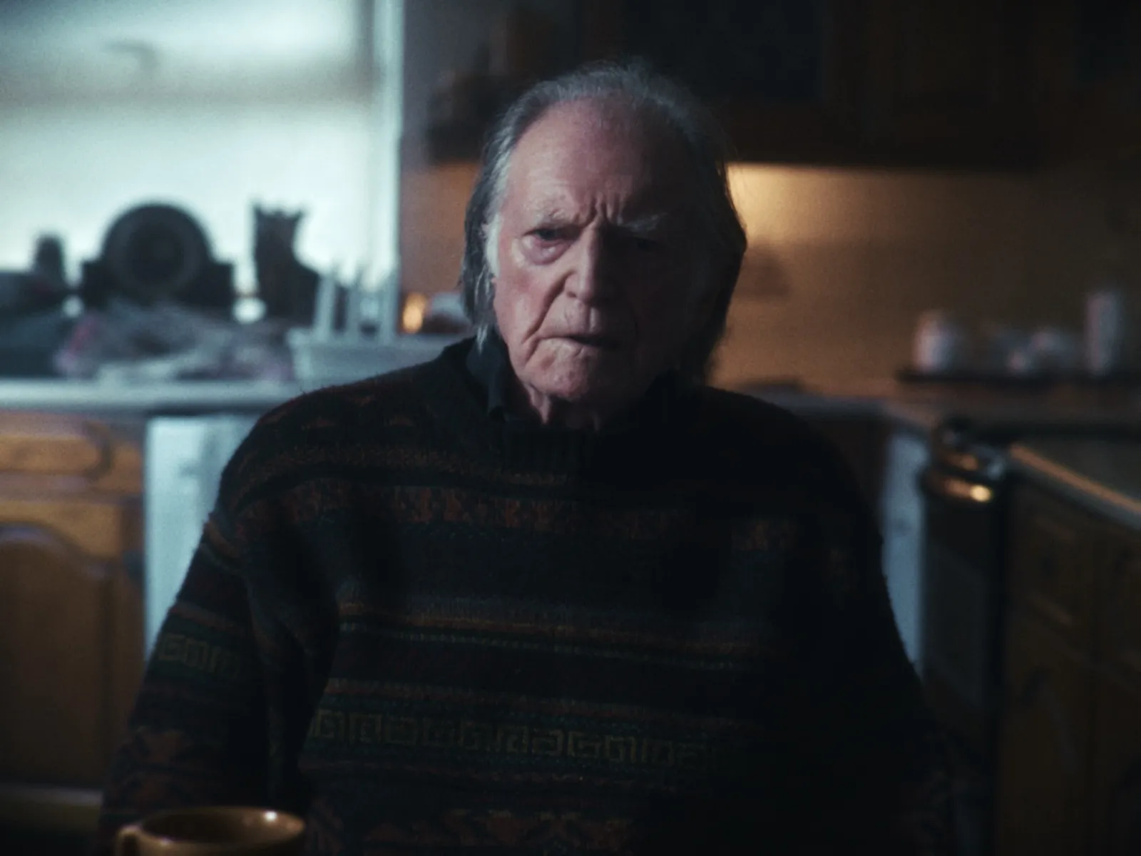 Actor David Bradley sitting in a dark room.