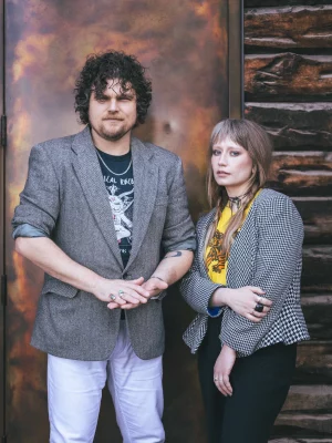 Joe and Shelby Maddock of the Plastic Cherries pose in blazers against a door