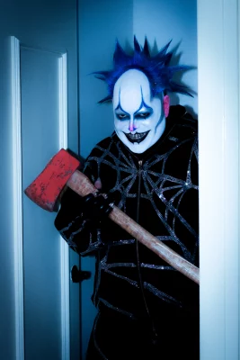 PJ Stinson aka Daddy the Clown in full makeup and costume, smiling deviously while holding what we hope is just a prop axe.