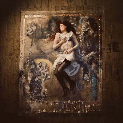 Florence Welch of Florence + the Machine lays on a rug on the ground