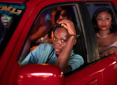 A woman drives a red car in Lady