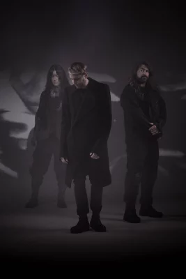 Three bandmates of HEALTH standing in a dark room.