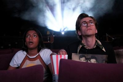 Charithra Chandran and Sebastian Croft sitting in a movie theater in How to Date Billy Walsh