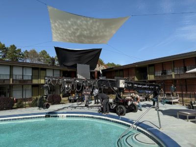 A camera crane on location for the DTF St. Louis set, shooting over an outdoor swimming pool.