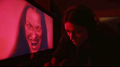 A woman on screen smiling wickedly.