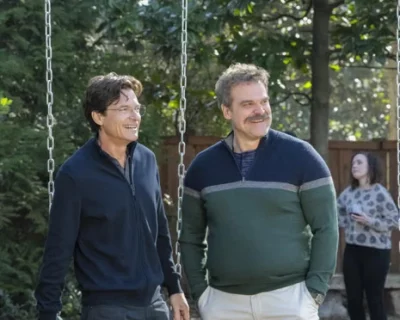 Two guys standing outside next to a swing set.