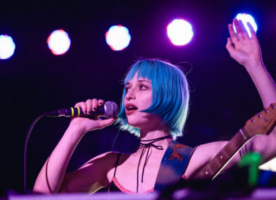 Oxis sings, one hand raised