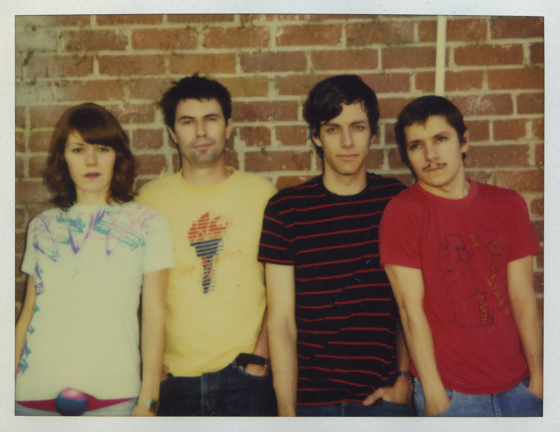 Four bandmates standing in front of a brick wall.