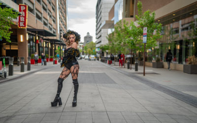 Baby Gorgeous wearing a corset, boa, tights and boots on the street