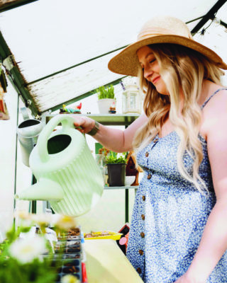 Rebecca Easter watering plants with a watering can.