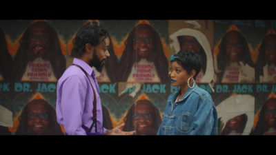 A man and a woman face one another in conversation in a scene from I Love Boosters.