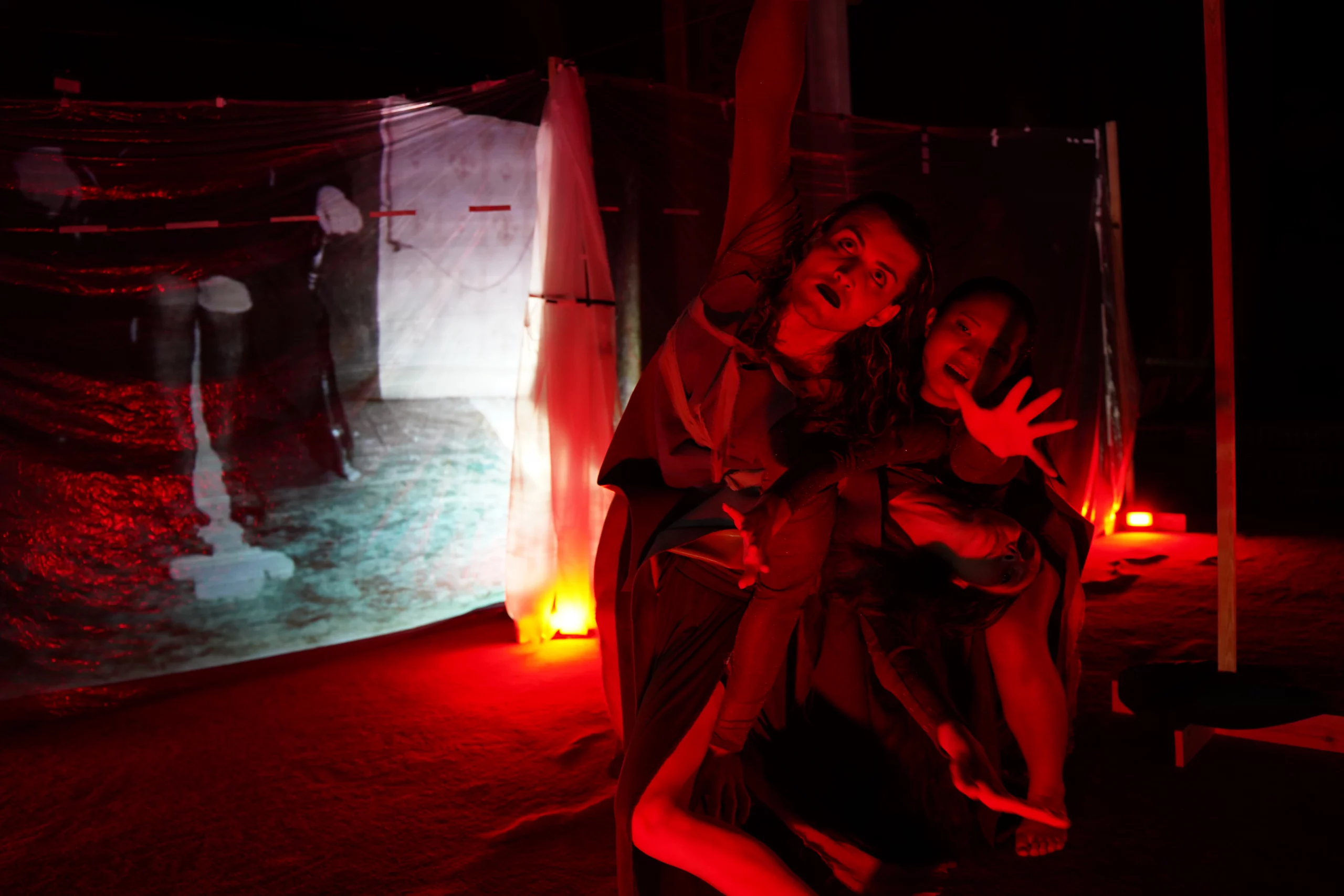 Two dancers in red lighting from "And you ghosts rise blue"