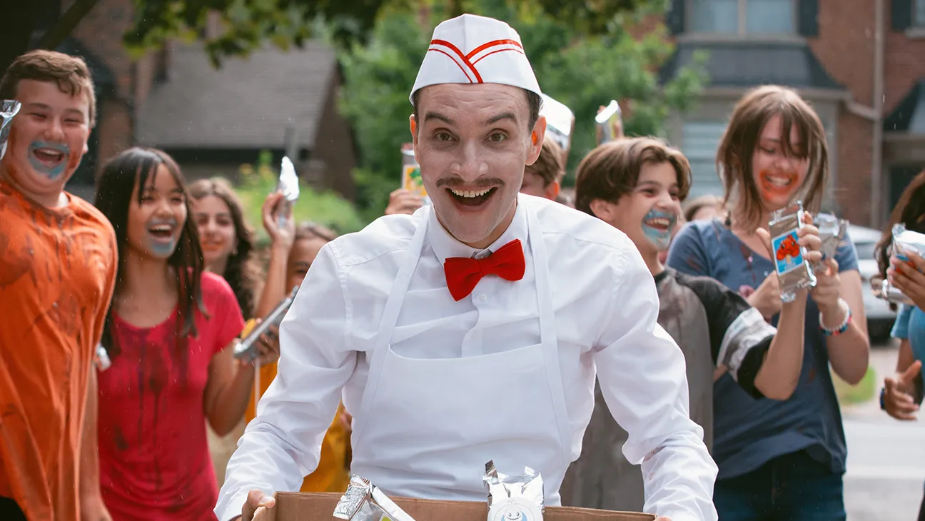 A man smiling at the screening with children eating ice cream behind him.