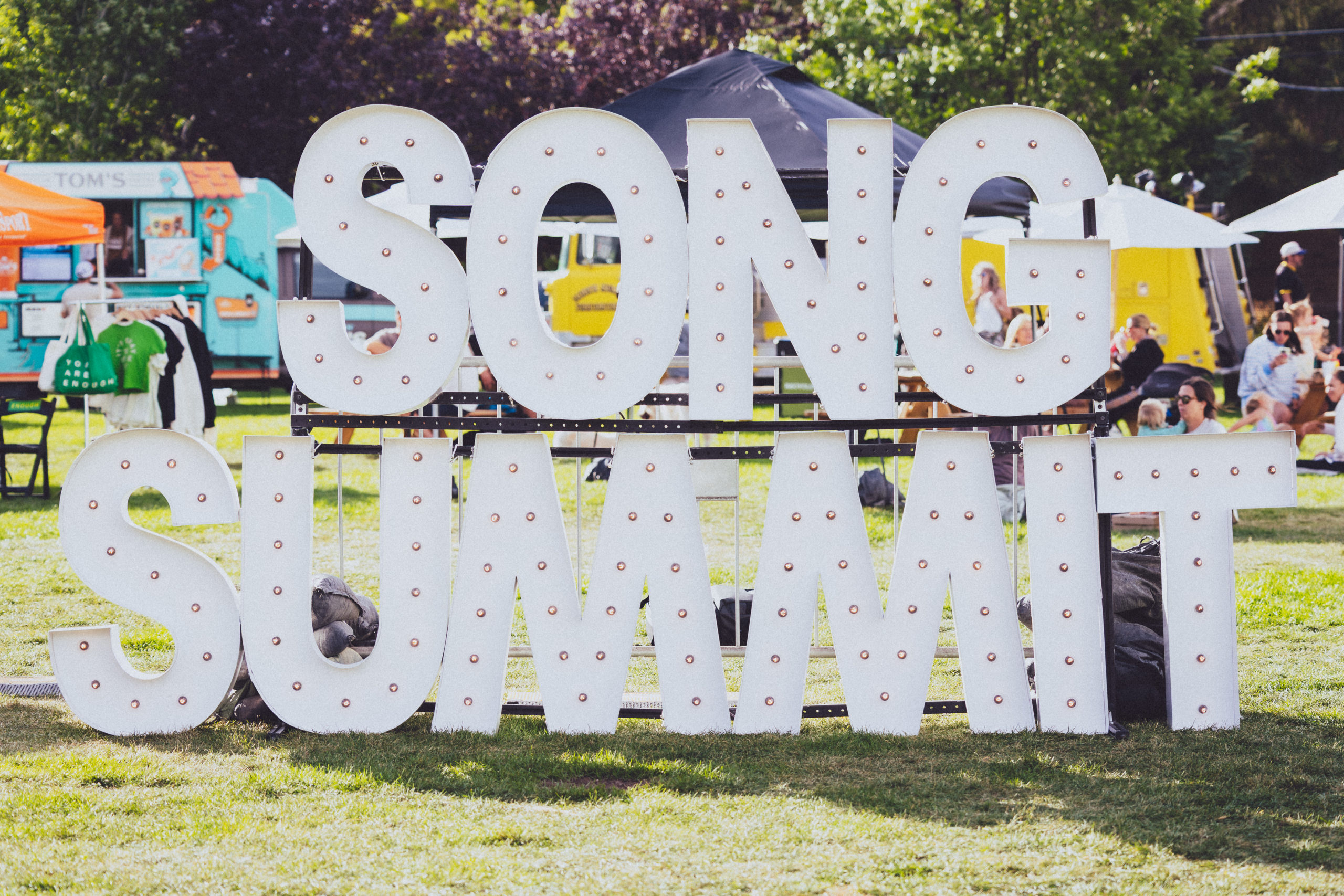 Song Summit structured sign in grassy field.
